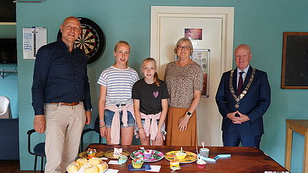 De jury van de cupcakewedstrijd op een rij voor een tafel met cupcakes